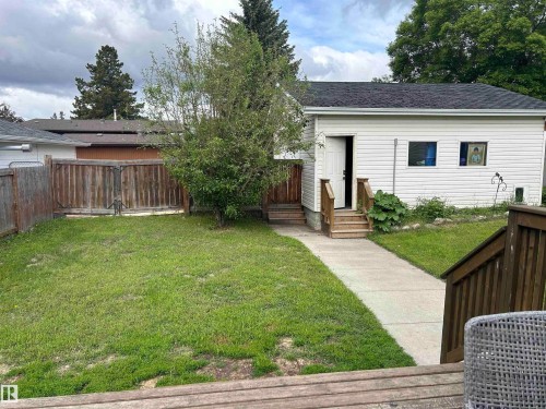 Expansive yard featuring a concrete walkway, mature tree, and wood fencing - 10924 30 Street, Edmonton, AB 