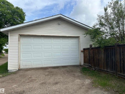 Detached garage featuring horizontal siding, a paneled overhead door, and an asphalt shingle roof - 10924 30 Street, Edmonton, AB 