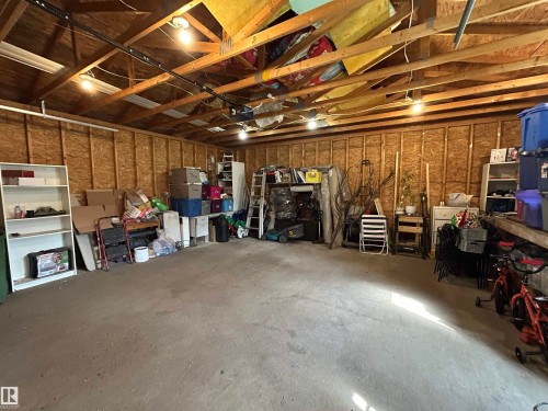 Spacious garage with exposed wood beam ceiling, concrete flooring, and ample overhead lighting - 10924 30 Street, Edmonton, AB 