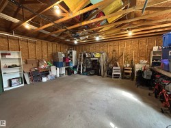 Spacious garage with exposed wood beam ceiling, concrete flooring, and ample overhead lighting - 
