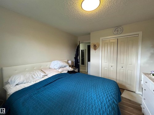Bedroom featuring light beige wall tones, a textured ceiling, and a flush-mount overhead light fixture - 10924 30 Street, Edmonton, AB 