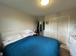Bedroom featuring light beige wall tones, a textured ceiling, and a flush-mount overhead light fixture - 