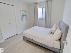 Bedroom featuring light wood-finish flooring, white walls, and a window with natural light - 