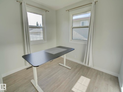 Room featuring light wood-finish flooring, white baseboards, and two windows with white trim - 9909 157 Street, Edmonton, AB 