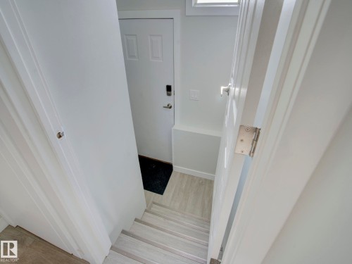 Staircase featuring light wood-finish flooring, white walls, and a window above the doorway - 9909 157 Street, Edmonton, AB 