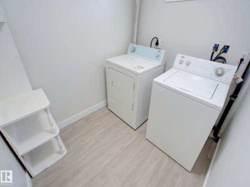 Dedicated laundry area featuring a washer and dryer, light wood-finish flooring, white painted walls, and built-in shelving - 9909 157 Street, Edmonton, AB 
