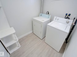 Dedicated laundry area featuring a washer and dryer, light wood-finish flooring, white painted walls, and built-in shelving - 