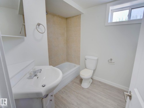 Bathroom featuring a white vanity with integrated sink, chrome faucet, and under-sink storage - 9909 157 Street, Edmonton, AB 