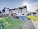 White siding residence with a dark roof and a front porch featuring wood railings and stairs - 9909 157 Street, Edmonton, AB 