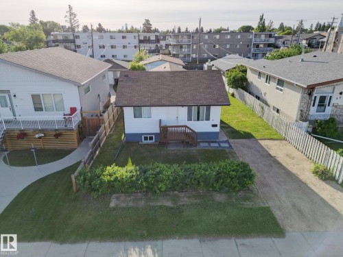 Detached single-story property featuring a dark shingle roof and white siding with a contrasting blue foundation - 9909 157 Street, Edmonton, AB 