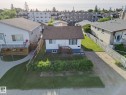 Detached single-story property featuring a dark shingle roof and white siding with a contrasting blue foundation - 9909 157 Street, Edmonton, AB 