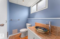 Bathroom featuring a decorative vessel sink, chrome single-handle faucet, tile countertop, and a built-in vanity with white cabinetry - 