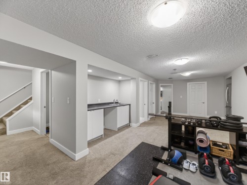 Finished basement area featuring a wet bar with a dark countertop and white cabinetry, recessed lighting, neutral-toned carpet flooring, and white trim - 15803 83 Avenue, Edmonton, AB 