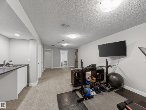 Lower level featuring a built-in wet bar with stainless steel sink, recessed lighting, and wall-mounted television - 15803 83 Avenue, Edmonton, AB 