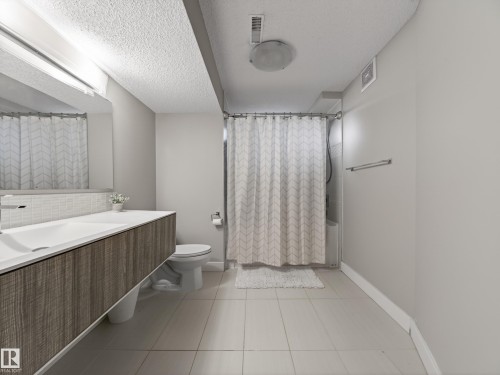 Modern bathroom featuring a floating wood-finish vanity with an integrated basin, contemporary faucet, and a subway tile backsplash - 15803 83 Avenue, Edmonton, AB 