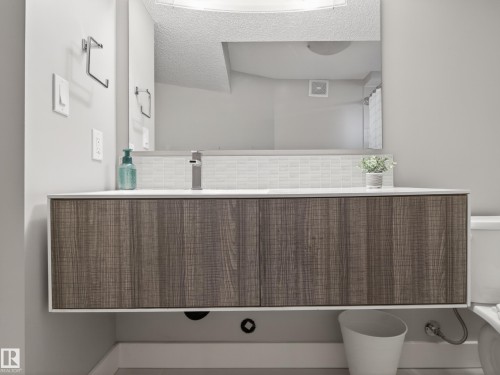 Floating wood-finish vanity with a white countertop and rectangular sink - 15803 83 Avenue, Edmonton, AB 