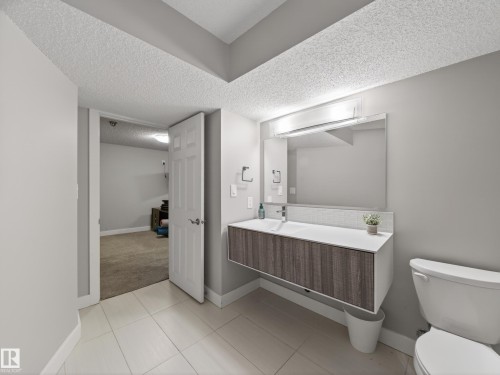 Contemporary bathroom featuring a floating wood-finish vanity with an integrated sink, a large wall-mounted mirror, and tile flooring - 15803 83 Avenue, Edmonton, AB 