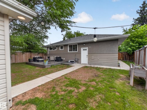 Backyard area featuring a raised wood-finish deck, concrete pathway, wood privacy fencing, and a built-in planter box - 15803 83 Avenue, Edmonton, AB 