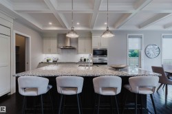 Kitchen featuring a large island with stone countertops, a stainless steel range hood, built-in microwave, integrated refrigerator, and dark wood-finish flooring - 