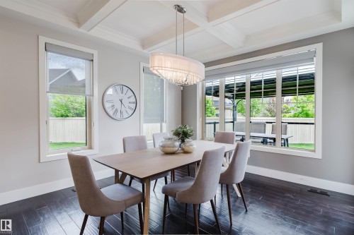 Dining area featuring dark wood-finish flooring, a coffered ceiling, and a contemporary chandelier - 3435 Keswick Boulevard, Edmonton, AB 