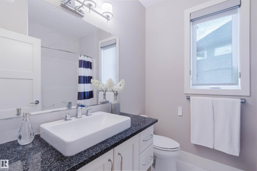 Bathroom vanity featuring a rectangular vessel sink, dark speckled countertop, and chrome faucet - 3435 Keswick Boulevard, Edmonton, AB 