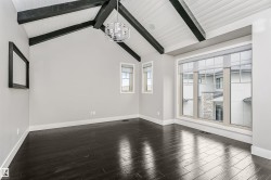 Vaulted ceiling with exposed black beams and white wood-finish planks, dark wood-finish flooring, large multi-pane windows, modern spherical chandelier, and a smaller rectangular window - 