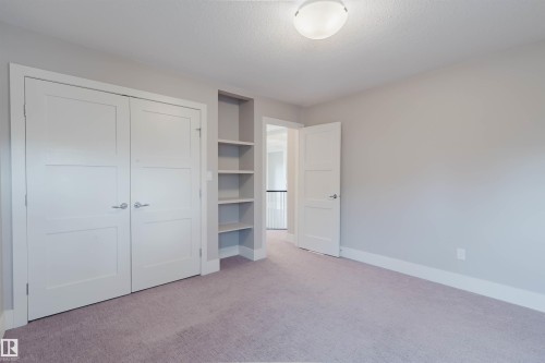 Plush carpeting throughout, featuring a built-in shelving unit, a flush-mount ceiling light fixture, and white trim - 3435 Keswick Boulevard, Edmonton, AB 