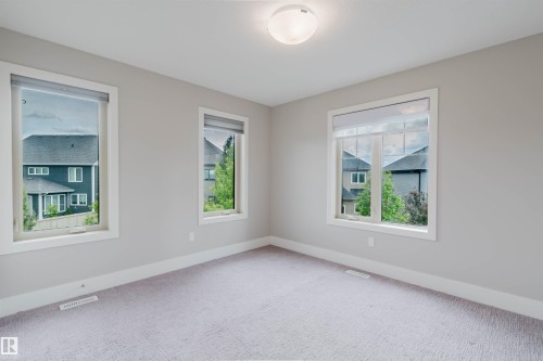 Neutral-toned room featuring a light-colored, patterned carpet and multiple large windows with white trim - 3435 Keswick Boulevard, Edmonton, AB 