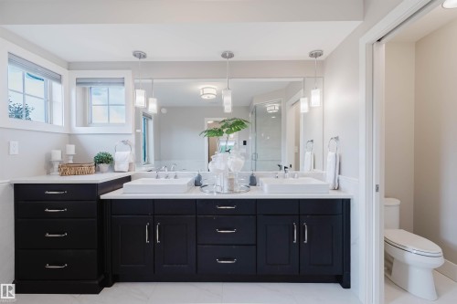 Dual vanity with dark wood cabinetry, white countertops, and integrated rectangular sinks - 3435 Keswick Boulevard, Edmonton, AB 