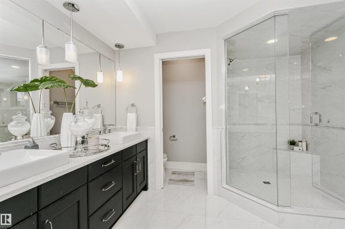 Spacious bathroom featuring a dual vanity with rectangular vessel sinks, dark wood cabinetry, and a large frameless glass shower enclosure - 3435 Keswick Boulevard, Edmonton, AB 