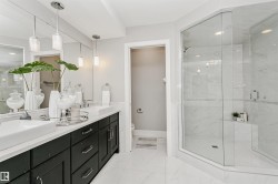 Spacious bathroom featuring a dual vanity with rectangular vessel sinks, dark wood cabinetry, and a large frameless glass shower enclosure - 