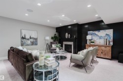 Spacious living area featuring light-toned carpeting, recessed ceiling lighting, and a prominent fireplace with a light-colored tile surround and dark mantelpiece - 