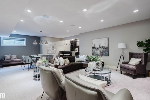 Open-concept lower level featuring recessed lighting throughout, a dining area with a linear pendant light fixture, a built-in wet bar with shelving, a window with horizontal blinds, and light-toned carpeting - 3435 Keswick Boulevard, Edmonton, AB 