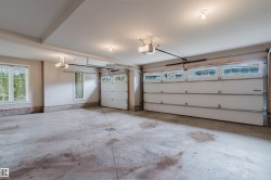 Spacious garage featuring two overhead doors with window panels, an additional single overhead door with window panels, multiple windows providing natural light, and ceiling-mounted garage door openers - 