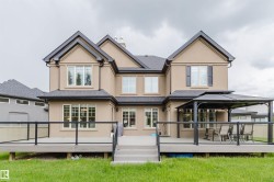 Expansive rear deck featuring glass panel railings, composite decking, and a set of exterior stairs - 