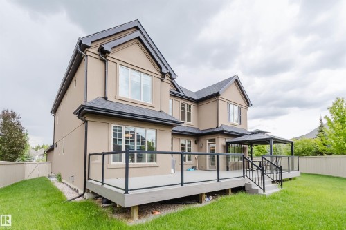 Expansive rear exterior featuring a multi-level deck with glass panel railings, a built-in gazebo, and a manicured lawn - 3435 Keswick Boulevard, Edmonton, AB 