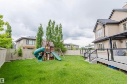 Expansive backyard featuring a manicured lawn, a privacy fence, and mature trees - 