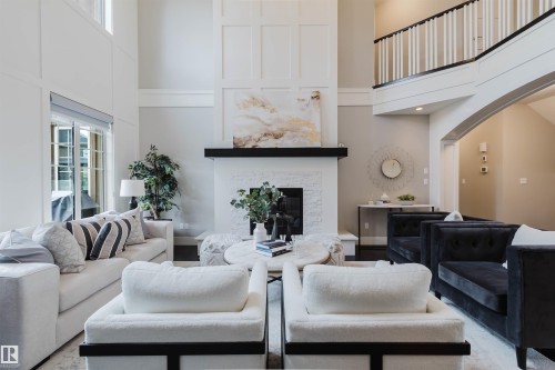 Living area featuring a two-story ceiling, wainscoting, a fireplace with a black mantel, and dark wood-finish flooring - 3435 Keswick Boulevard, Edmonton, AB 