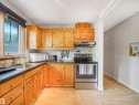 Kitchen featuring wood cabinetry, stainless steel sink, dark countertops, and light wood-finish flooring - 14612 93 Ave Nw, Edmonton, AB 
