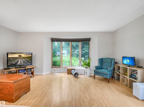 Spacious room featuring light wood-finish flooring, neutral wall tones, and a prominent bay window - 14612 93 Ave Nw, Edmonton, AB 