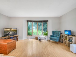 Spacious room featuring light wood-finish flooring, neutral wall tones, and a prominent bay window - 