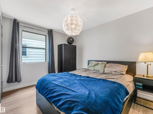 Bedroom featuring wood-finish flooring, a contemporary overhead light fixture, and a single window with white trim - 14612 93 Ave Nw, Edmonton, AB 