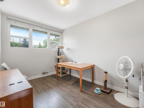 Room featuring light gray walls, wide baseboards, and wood-finish flooring - 14612 93 Ave Nw, Edmonton, AB 