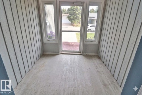 Enclosed porch featuring light wood-finish flooring, vertical paneling, and a full-light storm door with sidelight windows - 42 Alpaugh Crst, Leduc, AB 