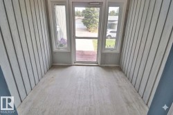 Enclosed porch featuring light wood-finish flooring, vertical paneling, and a full-light storm door with sidelight windows - 