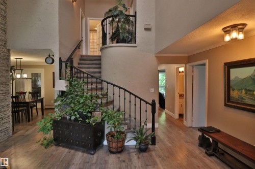 Grand entry featuring a curved staircase with wrought iron balusters and a carpeted tread - 42 Alpaugh Crst, Leduc, AB 