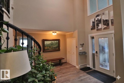 Grand entryway featuring a two-story ceiling, wood-finish flooring, and a decorative front door with side light - 42 Alpaugh Crst, Leduc, AB 