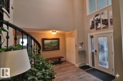 Grand entryway featuring a two-story ceiling, wood-finish flooring, and a decorative front door with side light - 