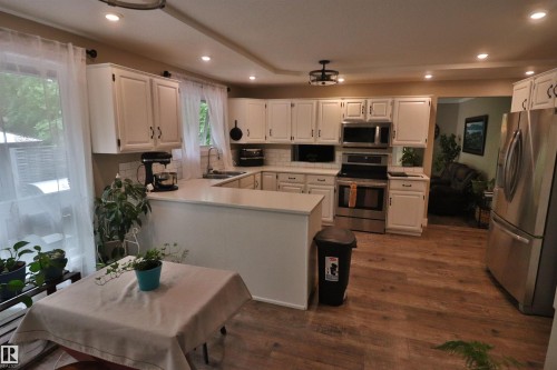 U-shaped kitchen featuring white cabinetry, light-toned countertops, and wood-finish flooring - 42 Alpaugh Crst, Leduc, AB 
