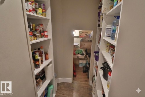 Walk-in pantry featuring extensive built-in shelving, wood-finish flooring, and light-toned walls - 42 Alpaugh Crst, Leduc, AB 